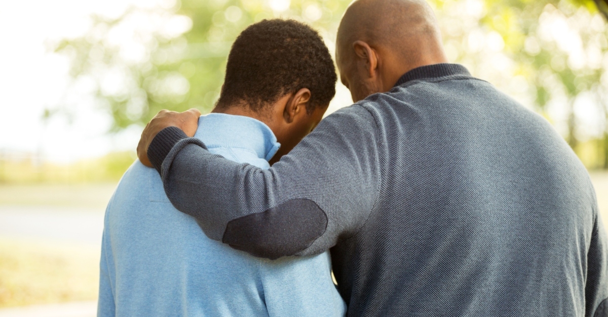 dad with arm around teen son