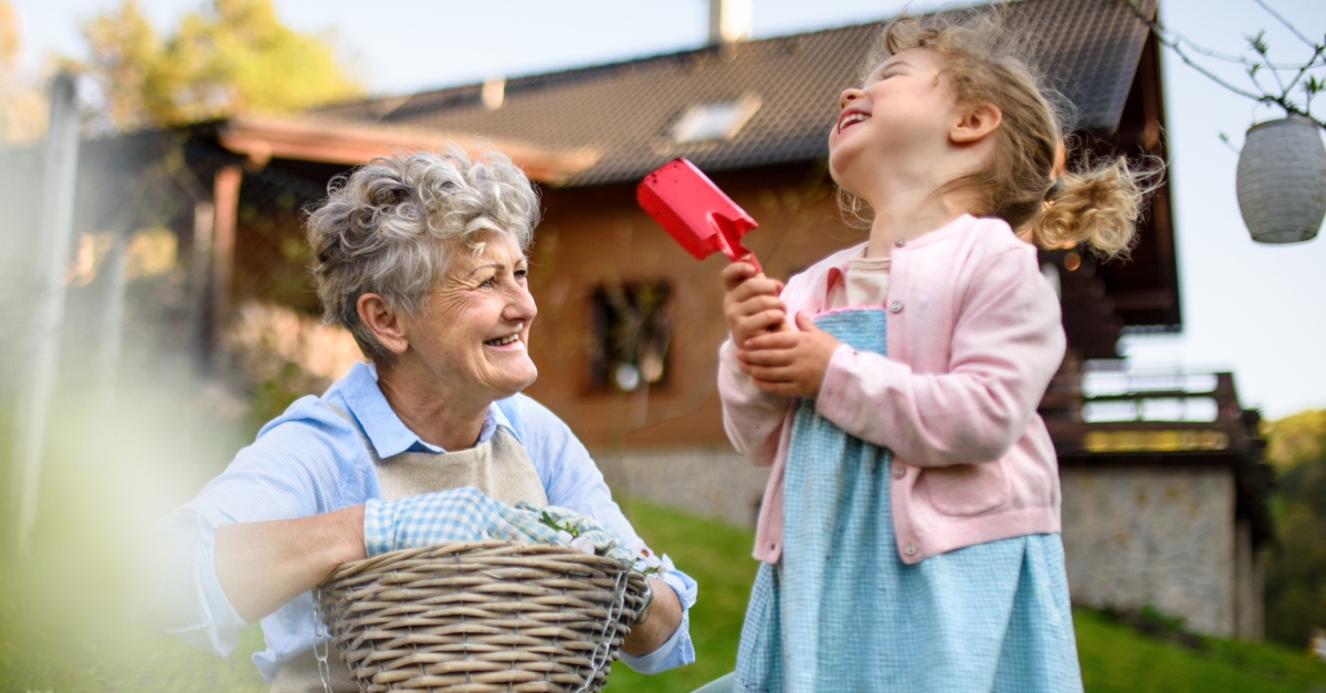 senior grandmother gardening with joyful granddaughter