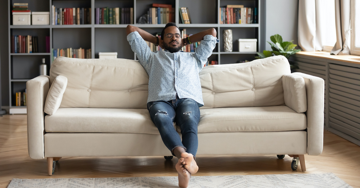 man resting and relaxing on sofa with bookshelf behind him, resting in the Lord