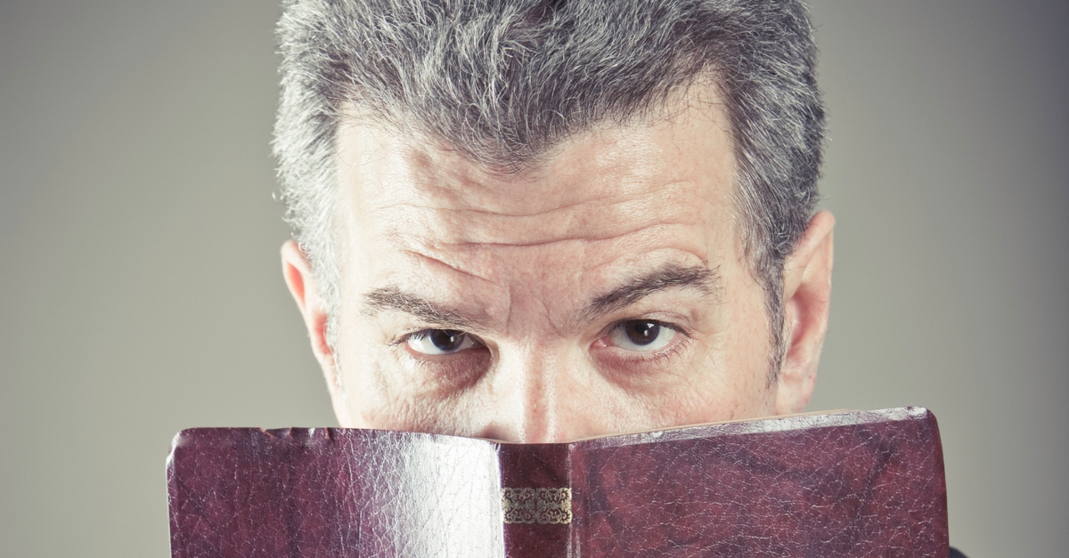 man peering over top of open Bible