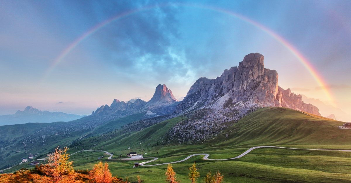 mountain range in beautiful green landscape with rainbow
