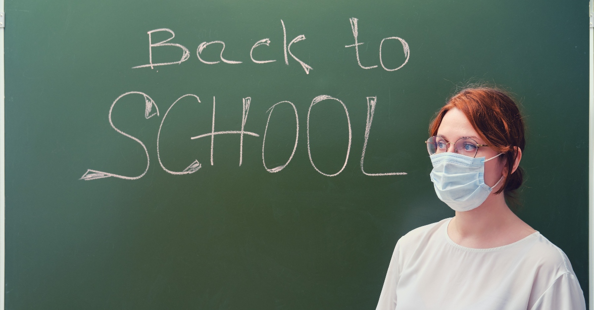 teacher wearing mask in front of blackboard with back to school written in chalk, challenges teachers face covid