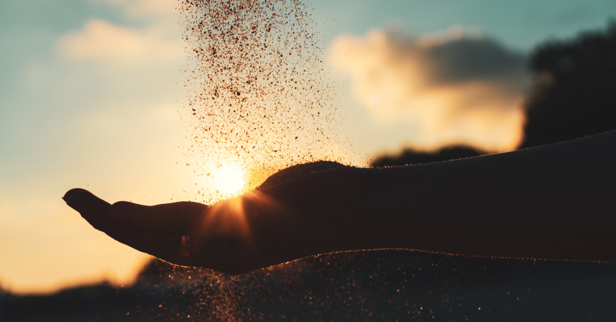 sand pouring through open palm to signify holding loosely or letting go