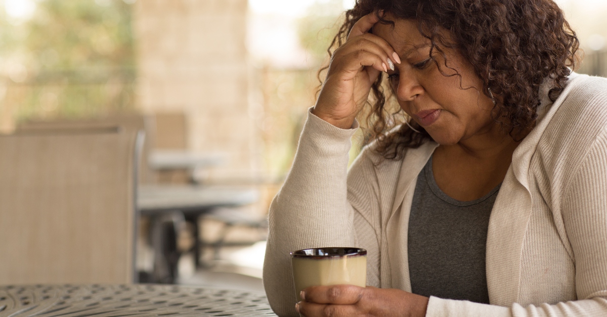 woman looking worried and sad sitting with a cup of coffee