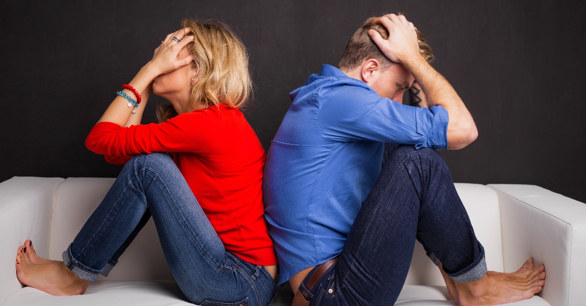 couple sitting back to back on couch looking upset, how to love someone when theyre angry