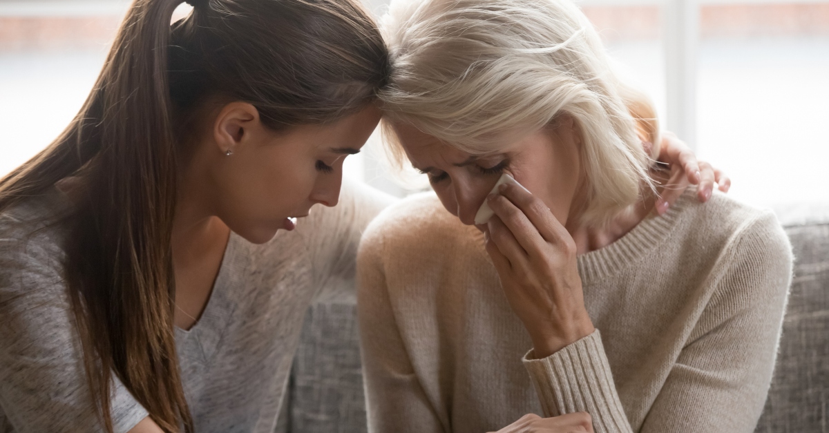 adult daughter consoling grieving senior mom