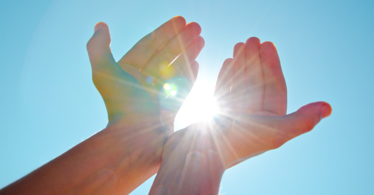 hands up to bright sun bursting through