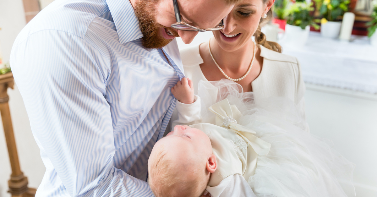 young couple holding baby in church for dedication or baptism, prayer for pregnancy