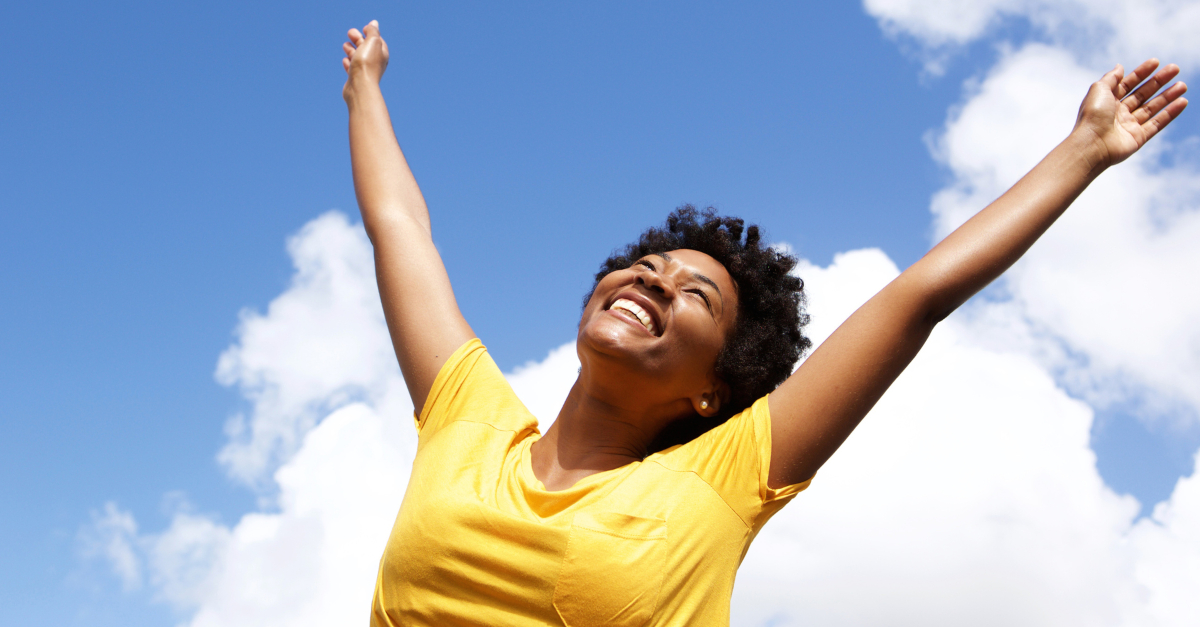 joyful woman with hands raised in praise and free of worry