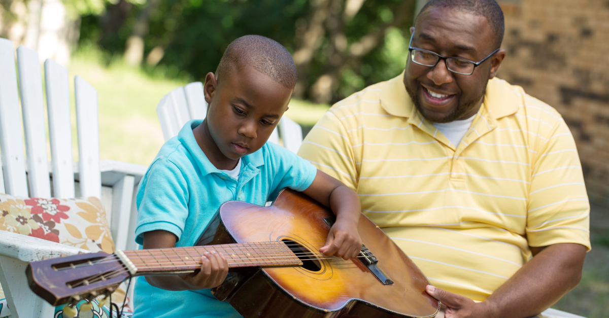 dad teaching son to play guitar