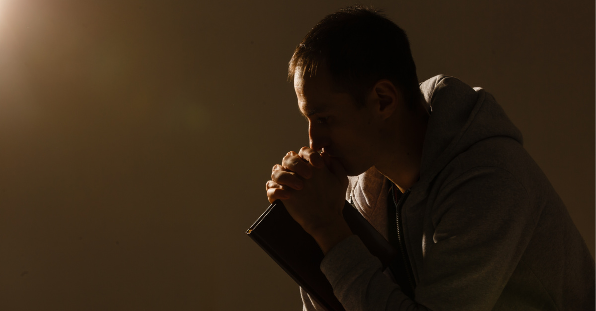 A man praying and holding a Bible, man forgives the guy who killed his wife