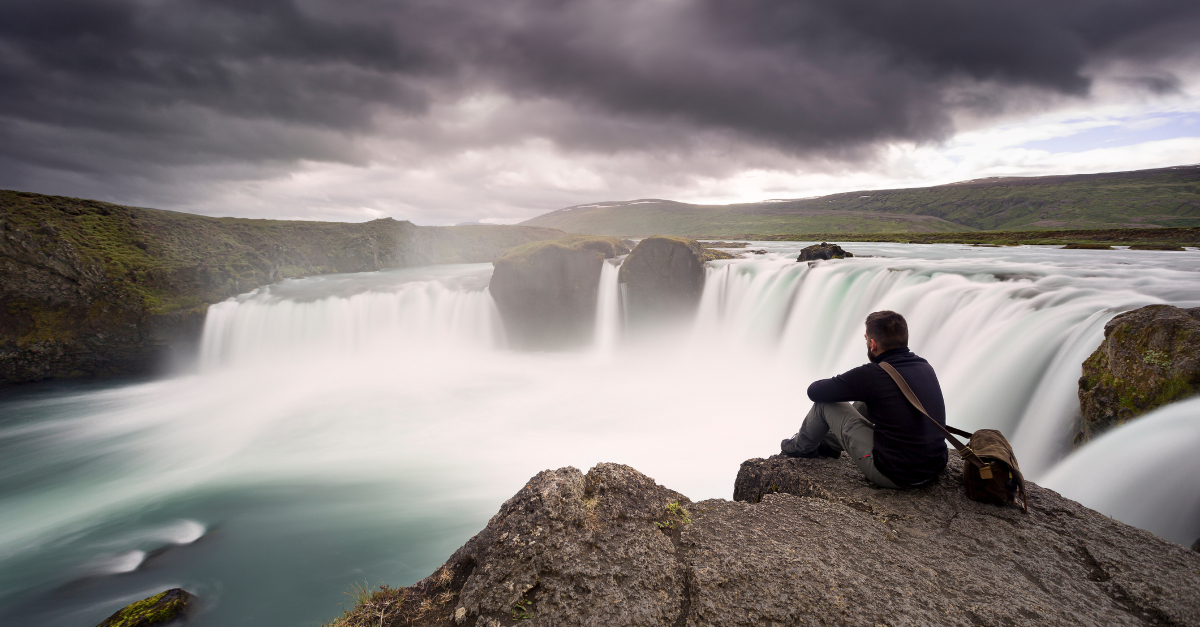 man marveling in awe at edge of waterfall - god-fearing