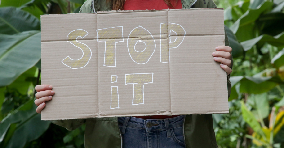 woman protesting holding up stop it sign