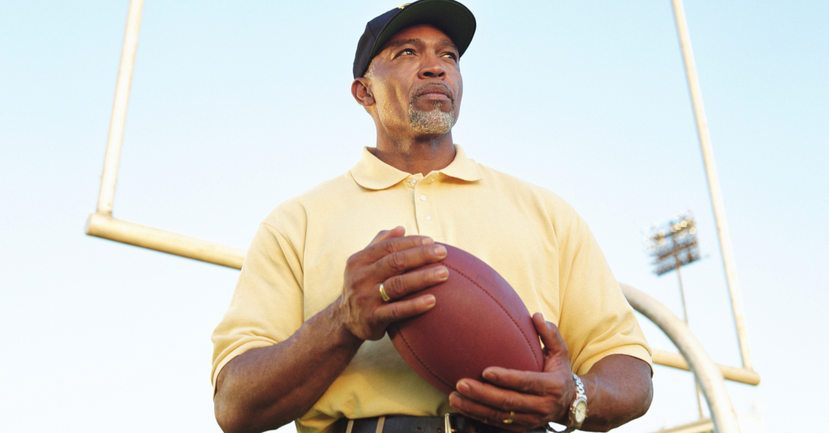 upshot of football coach at goalpost looking up