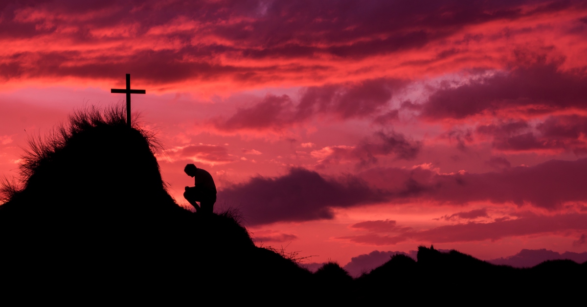 Man kneeling in front of the cross on Golgatha, living water