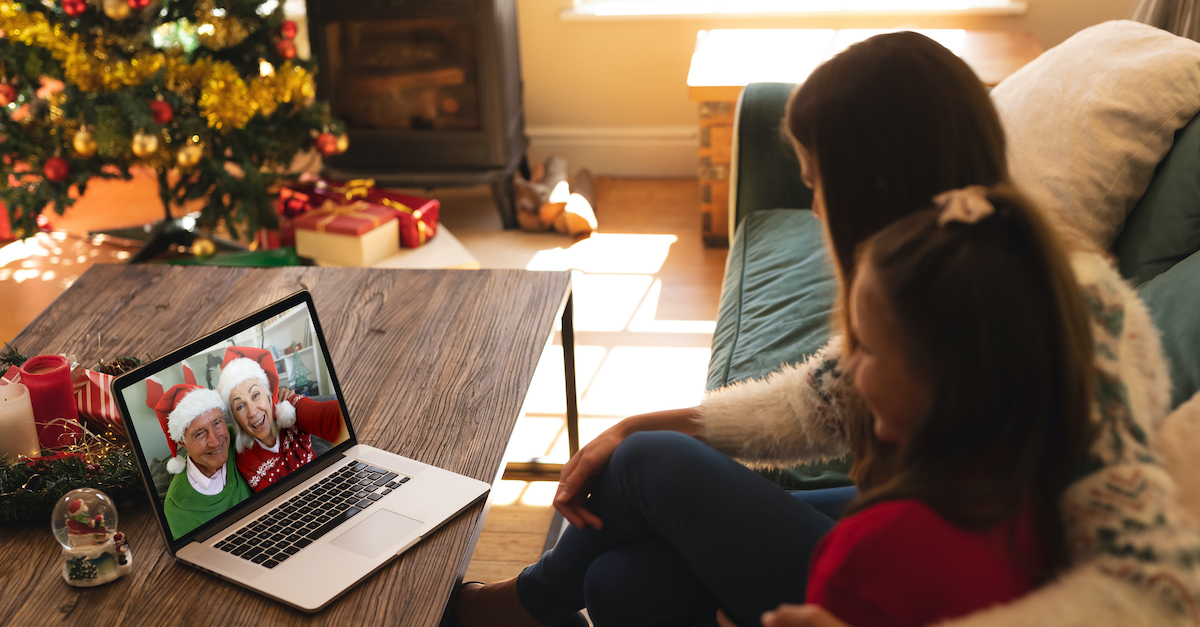 Mom and daughter face-timing grandparents on laptop at Christmas time