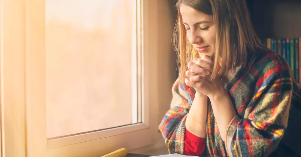 woman praying by window