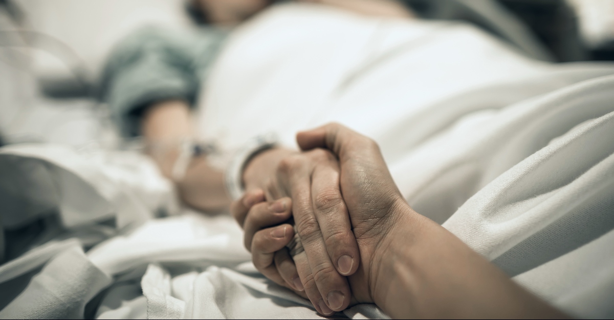 Hand holding on a hospital bed