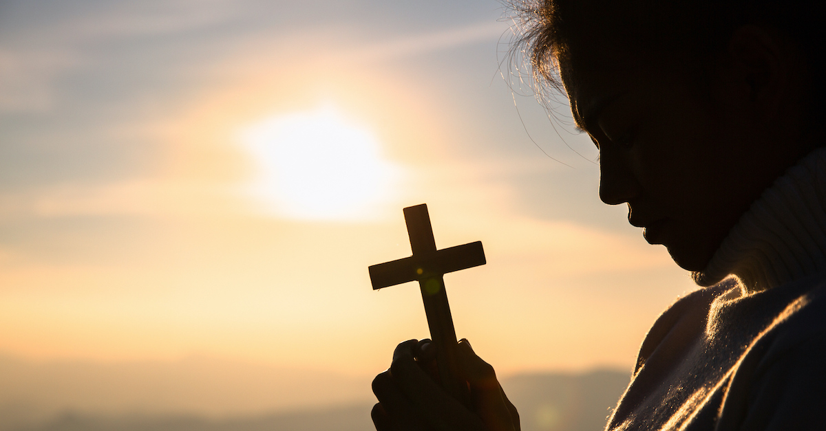 woman holding a cross and praying, Holy Week prayer