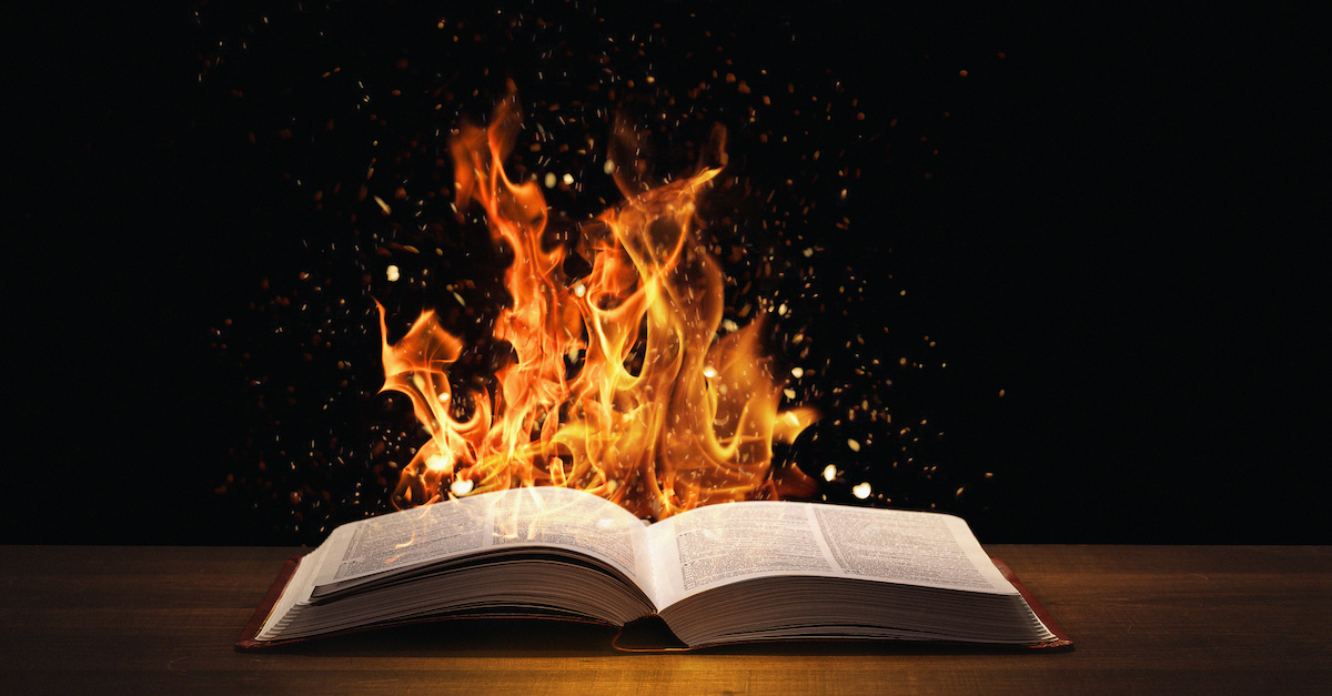 open Bible on table with flames rising behind it, seven deadly sins