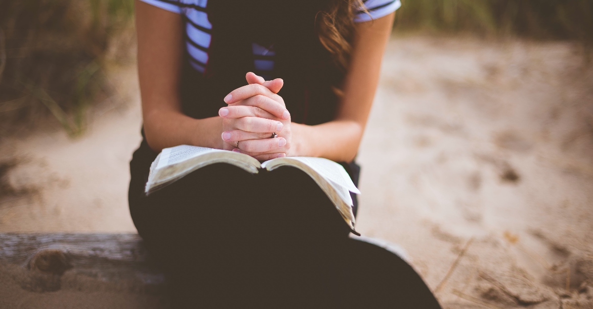 woman praying with bible open outside