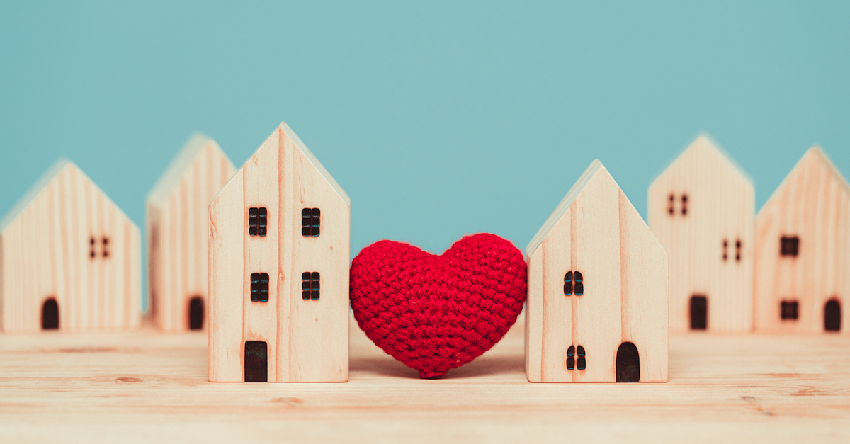 model wooden houses with a red crochet heart in the middle, love is patient love is kind