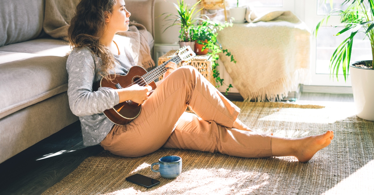 young woman playing music instrument at home alone