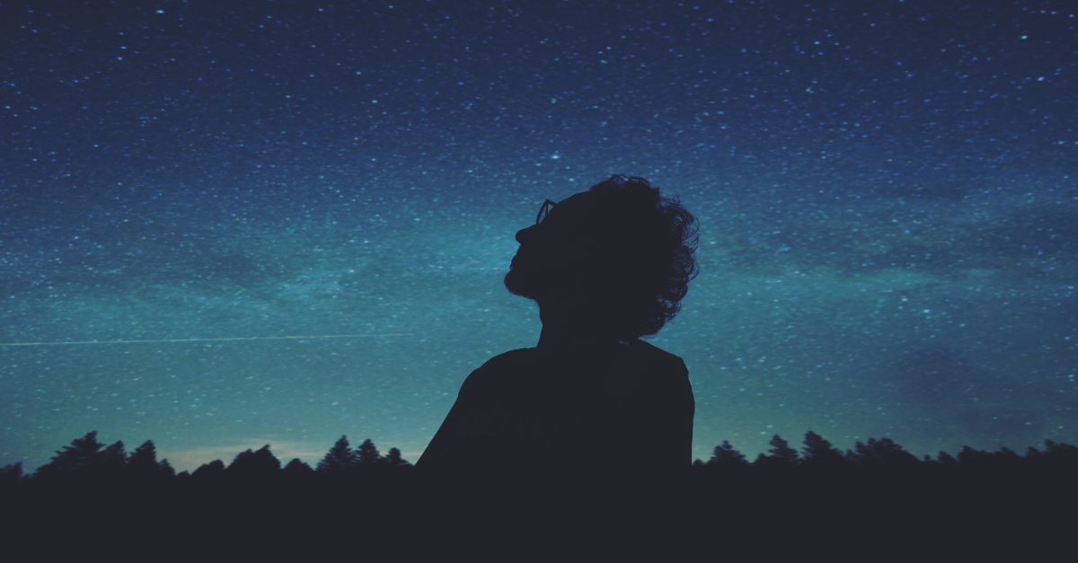 man looking up at night sky stars