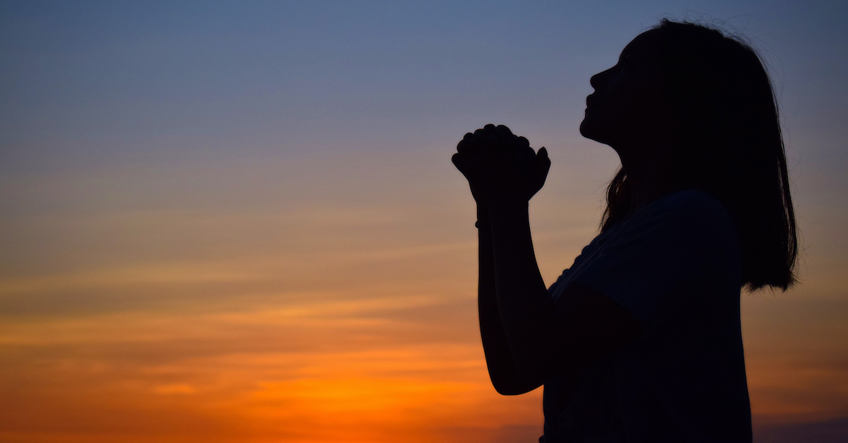silhouette of woman praying at sunset