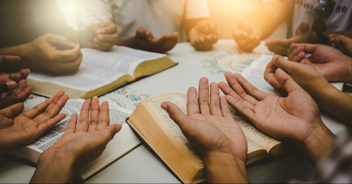 Hands held upward in worship on Bibles