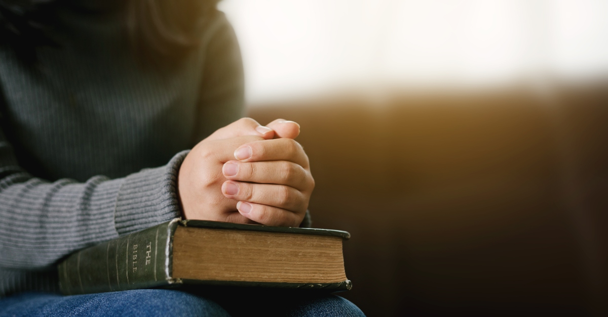 Woman with hands folded on a Bible