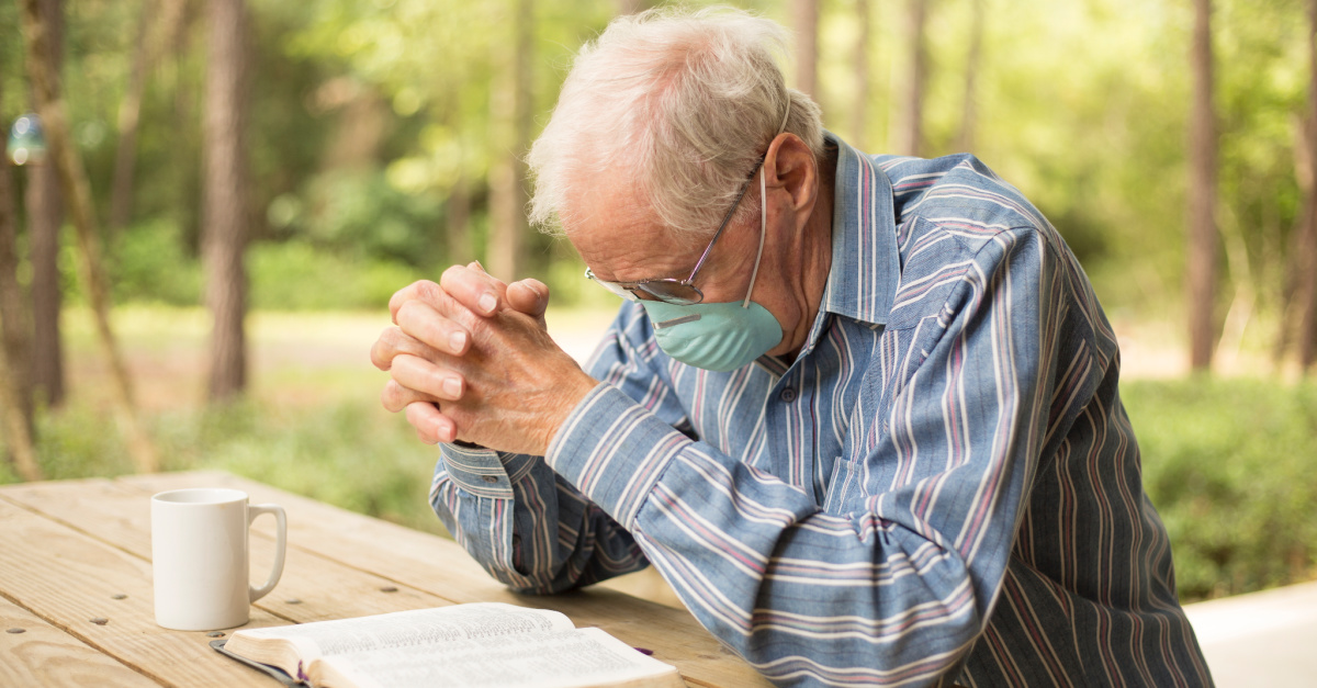 An older man praying while sitting outside