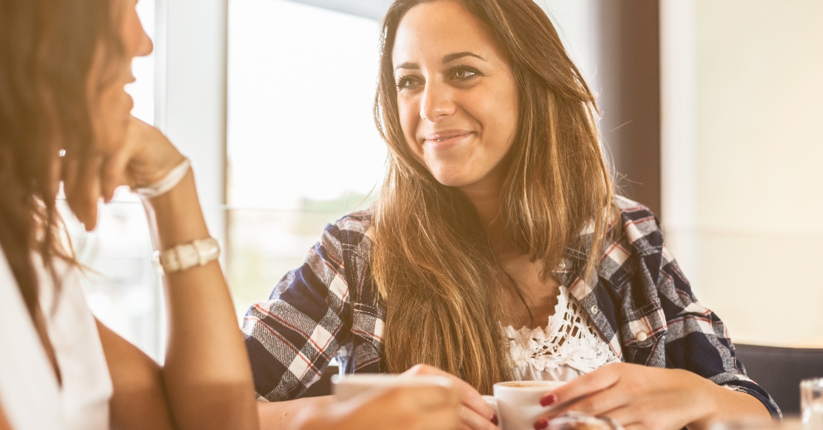 friend smiling listening to friend having coffee