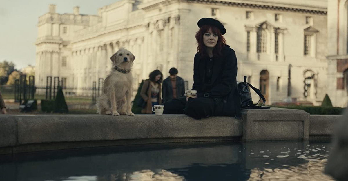 Emma Stone and a dog sitting at a fountain in Cruela