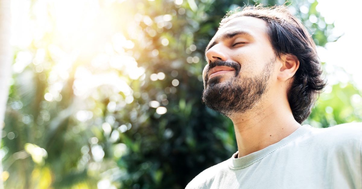 man outside nature eyes closed smiling happy content