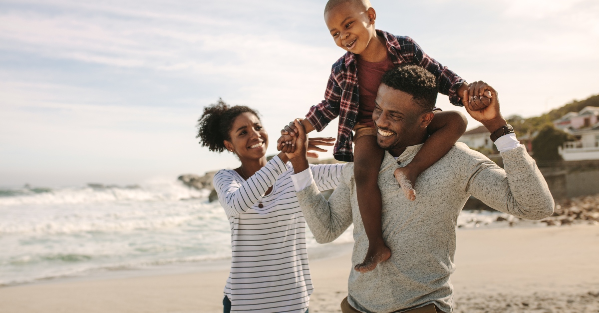 family laughing walking together on beach