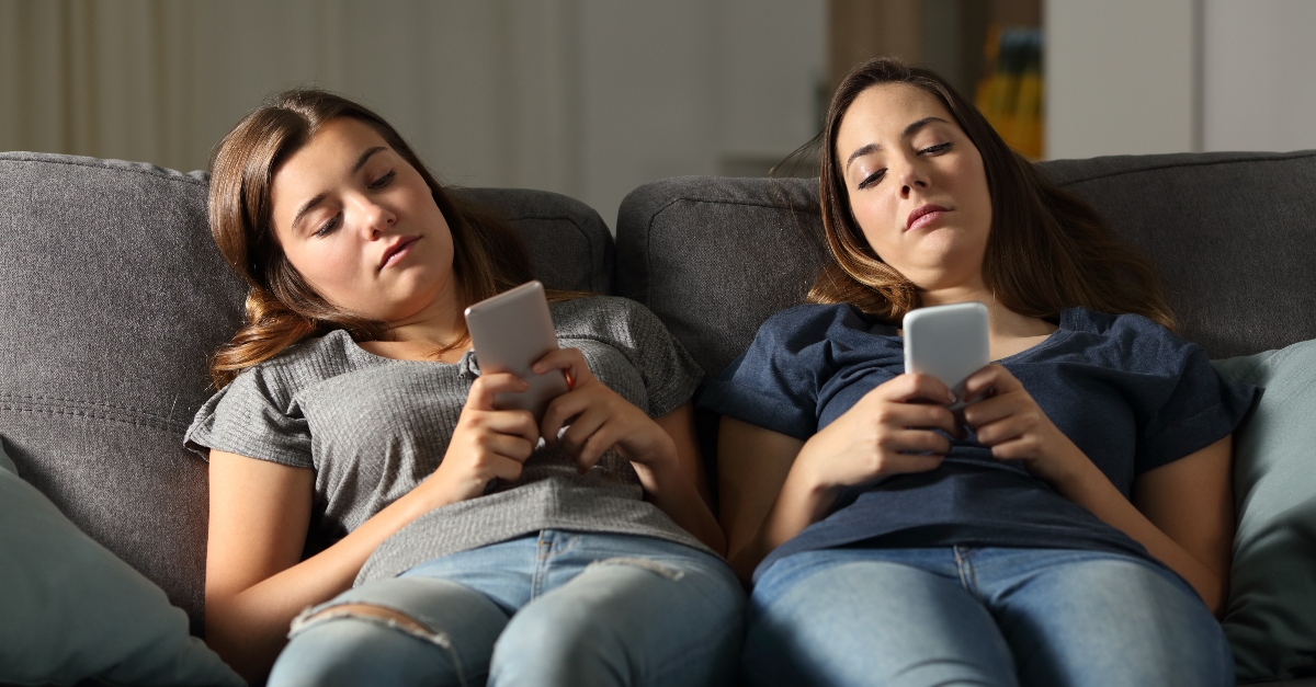 women sitting on couch not talking staring at phones