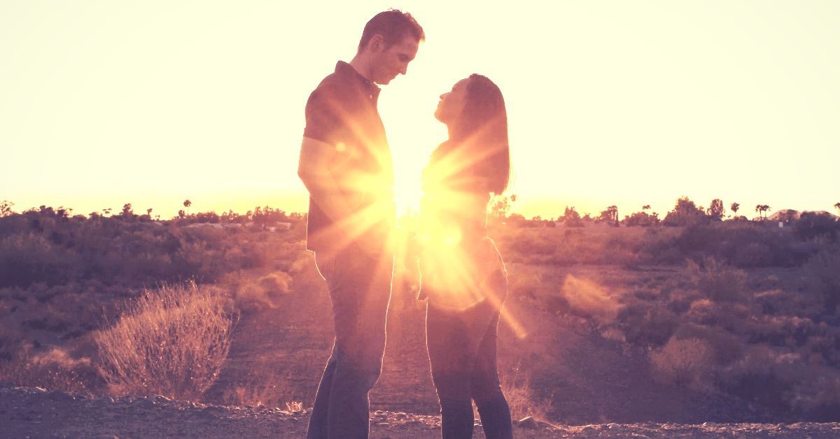 couple facing each other outdoors sunburst between them