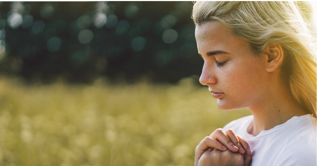 A young woman praying outside