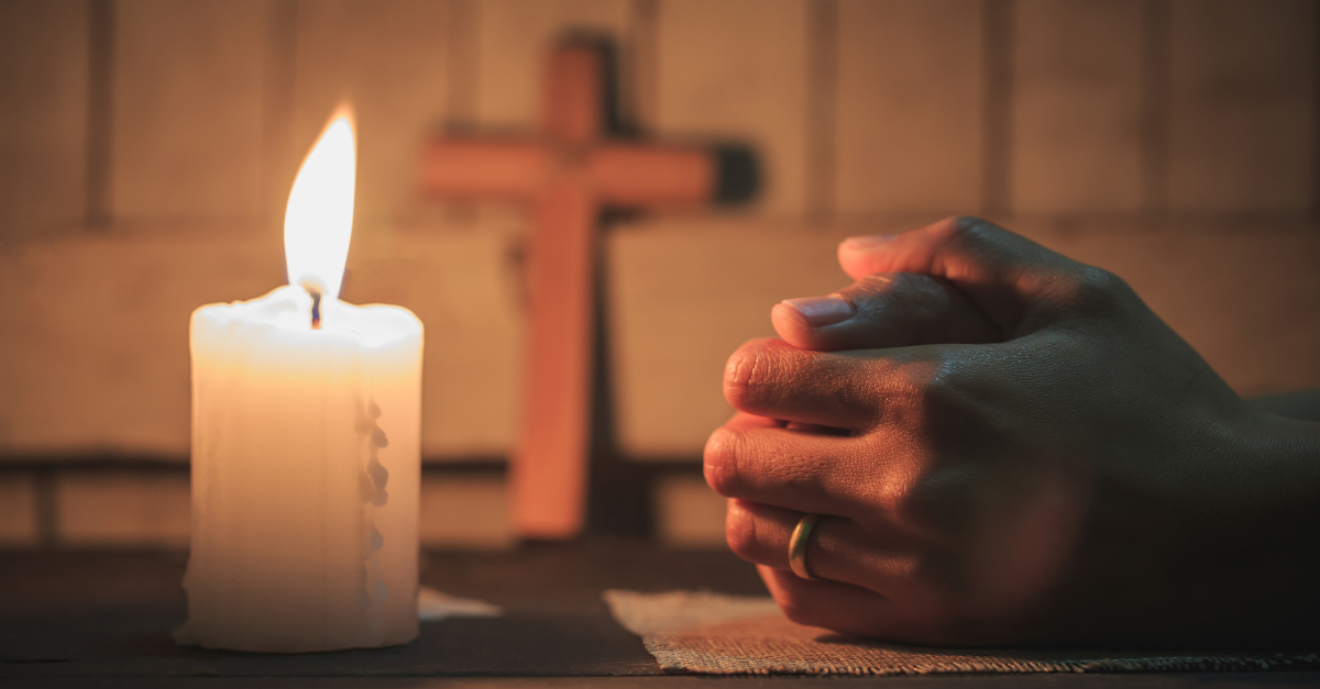 prayer hands with candle and cross