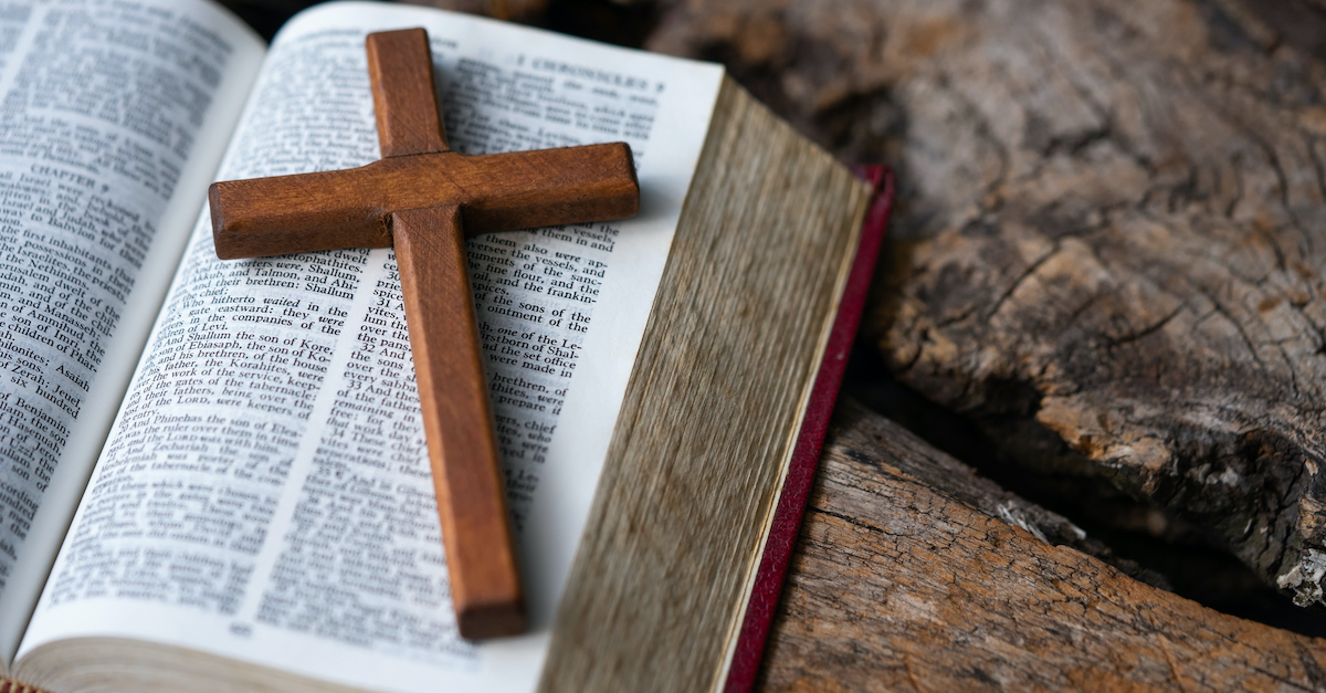 wooden cross laying on open Bible pages