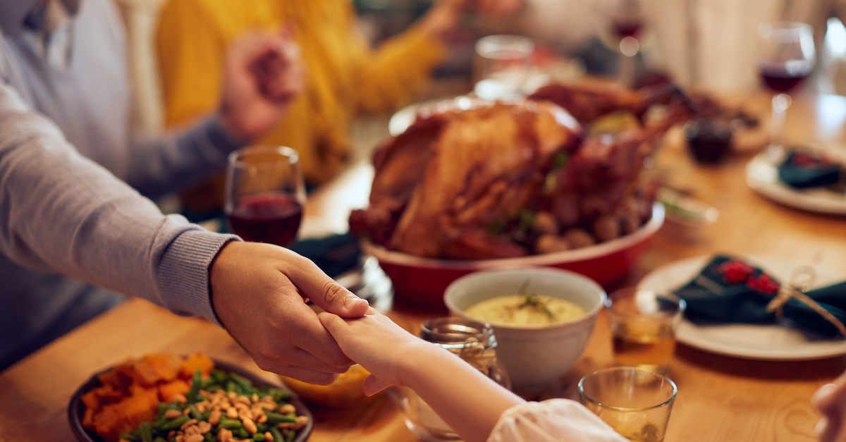 Family praying holding hands at Thanksgiving dinner
