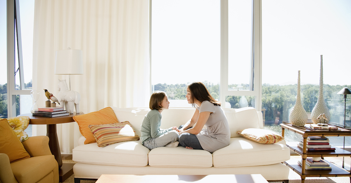 mother and young daughter talking on couch