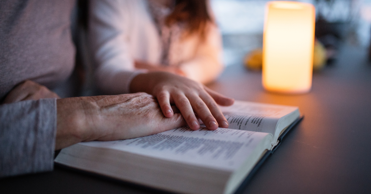 little girl and grandmother reading bible at home