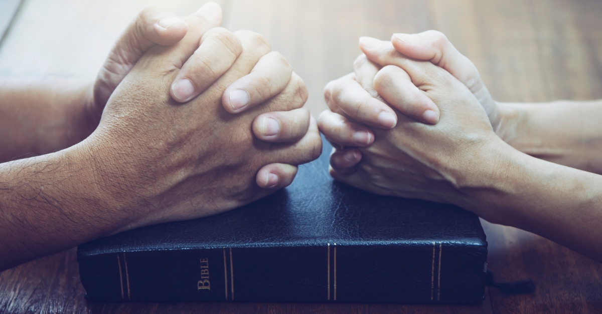 Man and woman praying over a Bible together