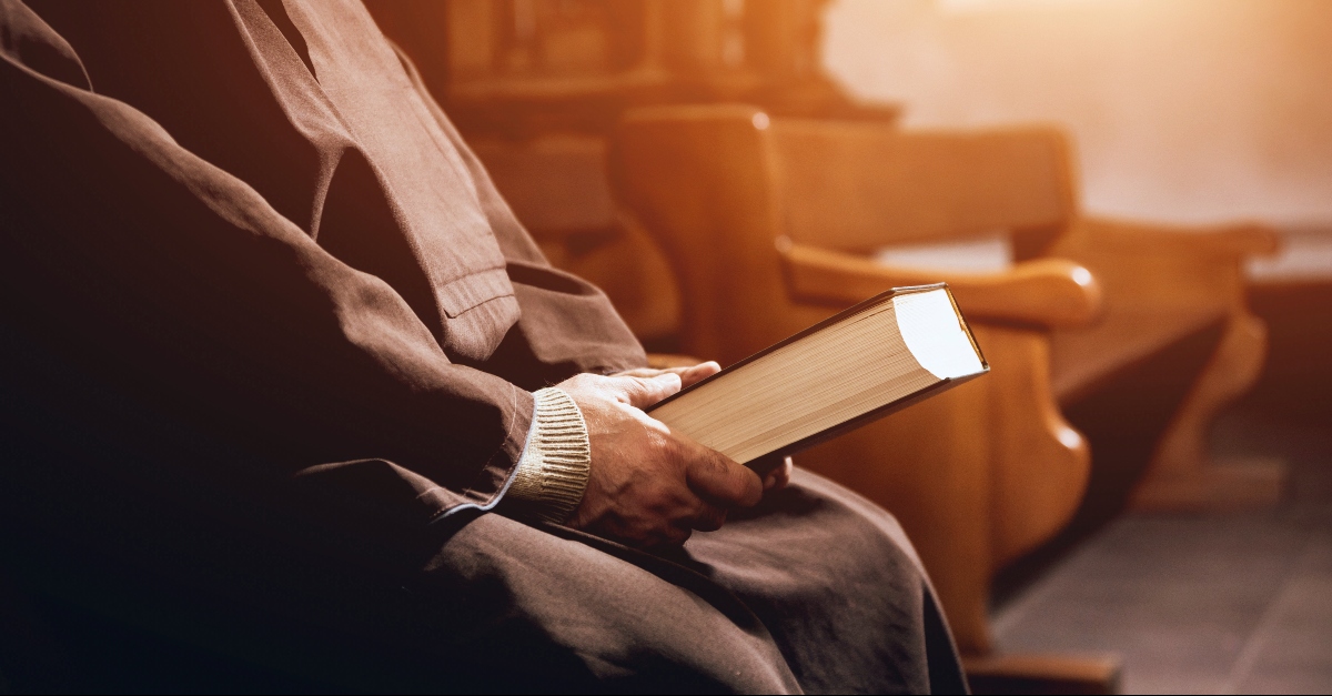 Pastor holding a Bible in a pew, prayer for pastor