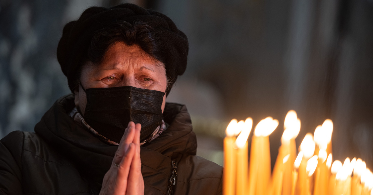 a Ukrainian woman praying before lit candles