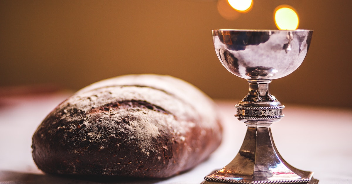 communion or eucharist set on table with loaf of bread and silver chalice