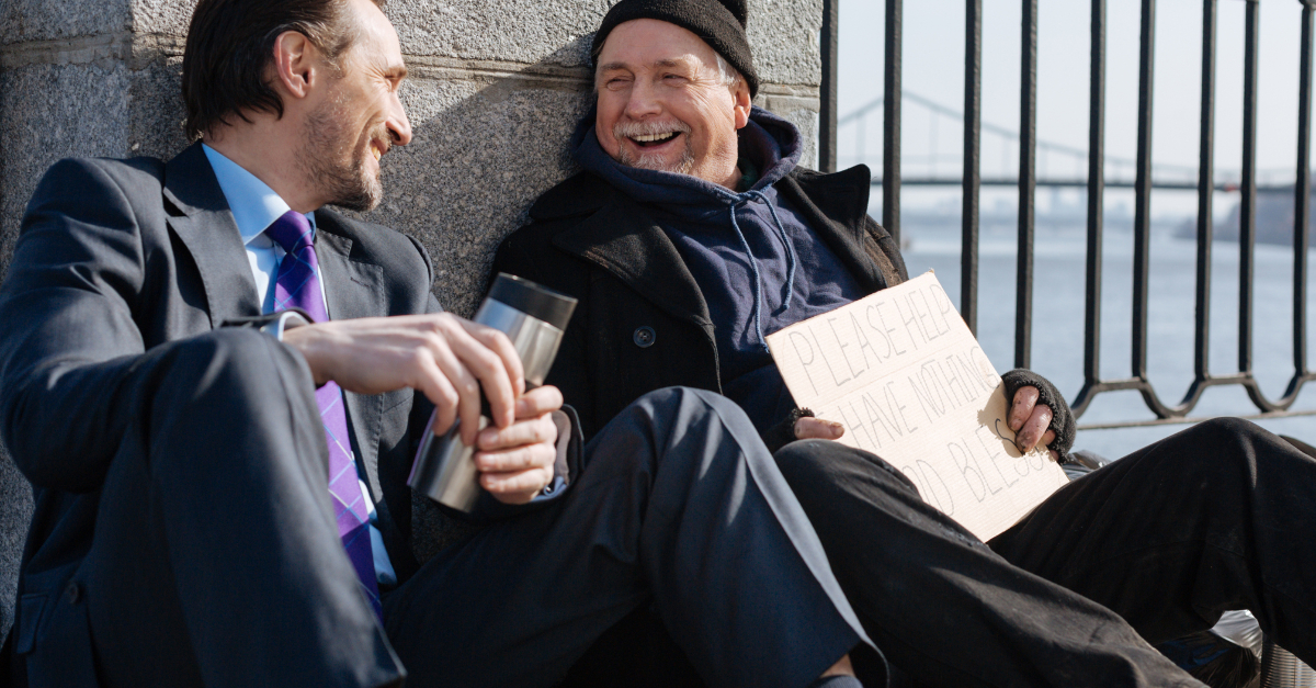 Business man sitting and talking with homeless man