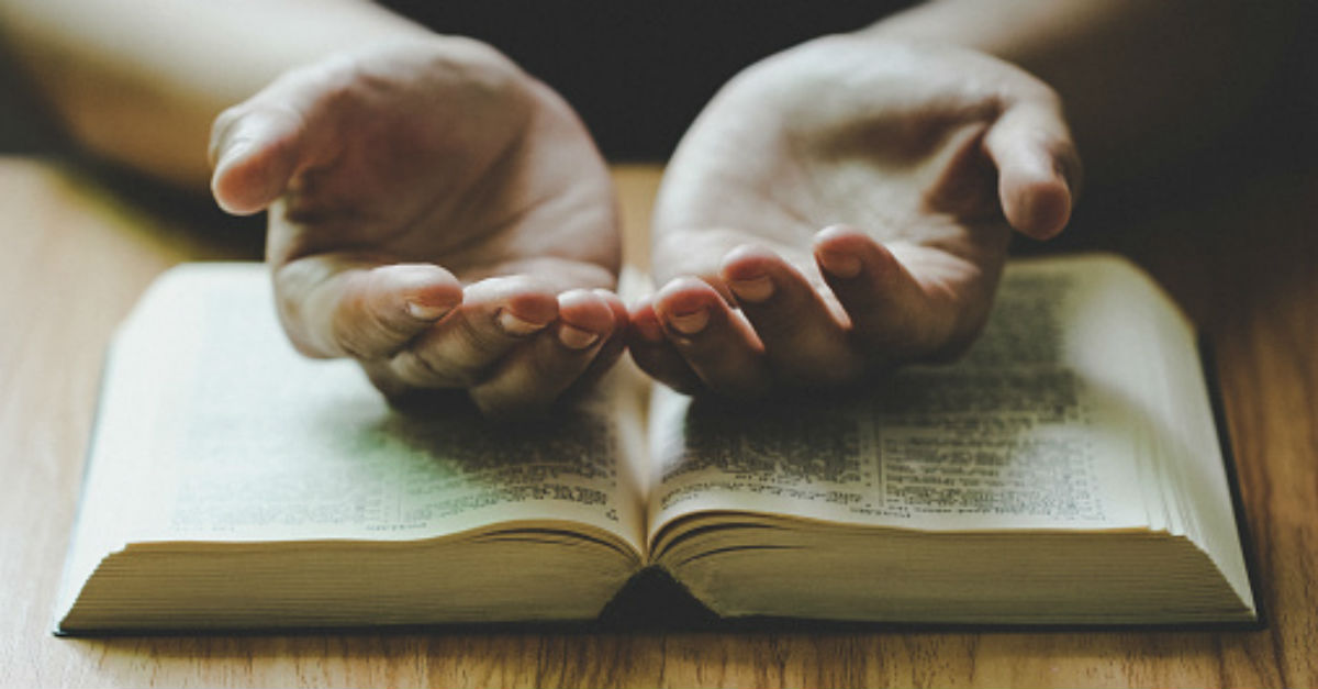 Open hands on top of a Bible